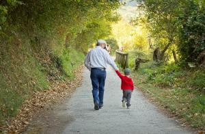 Grandfather and grandchild walking down a nature path holding hands